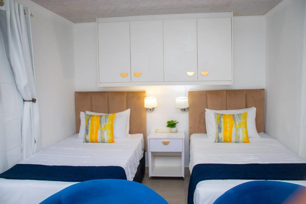 two beds in a small room with white cabinets at Optimum Stay Self Catering Accommodation - Twin Room 2 Single Beds in Parow