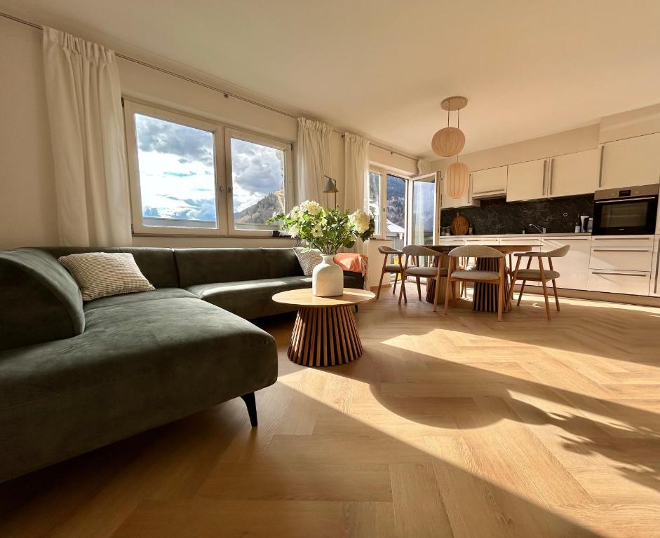 a living room with a green couch and a kitchen at Spacious boutique family apt w sunny balcony & mountain views in Zell am See