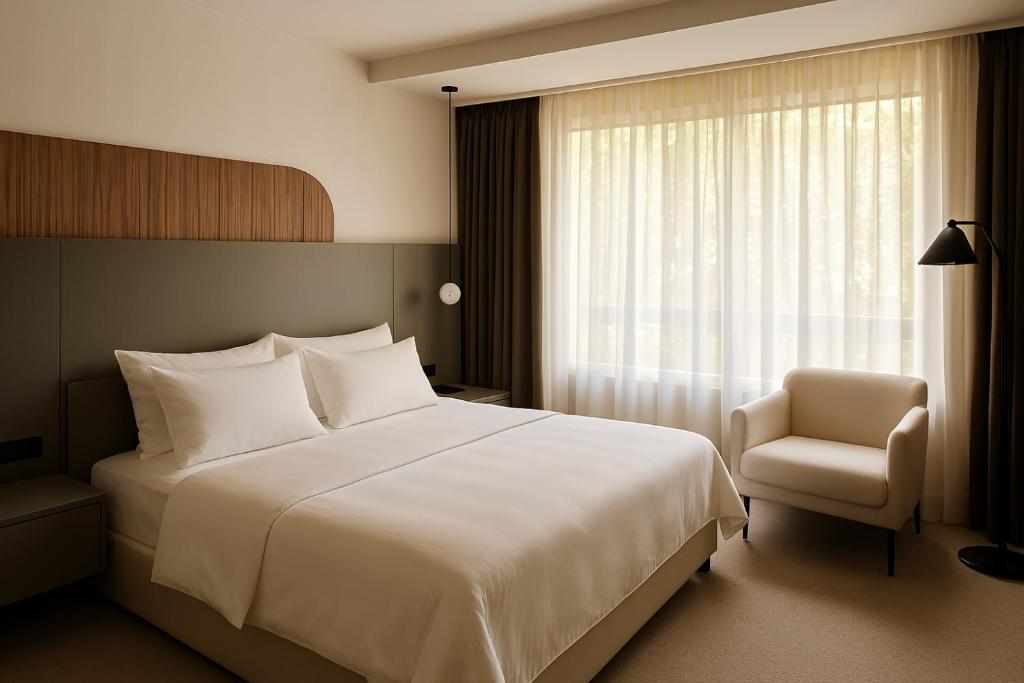 a bedroom with a bed and a chair and a window at Awen Hotel Vechta in Vechta