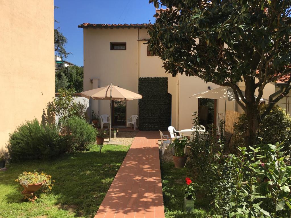 um jardim com um guarda-sol e uma casa em Guest House Il Naif em Florença