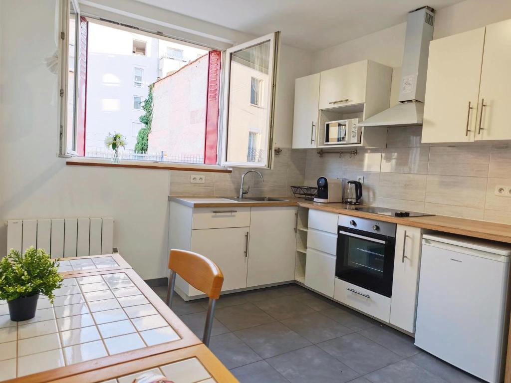 une cuisine avec des armoires blanches, une table et une fenêtre dans l'établissement Comfortable Loft and apartment for 2 or 4 persons, à Alfortville