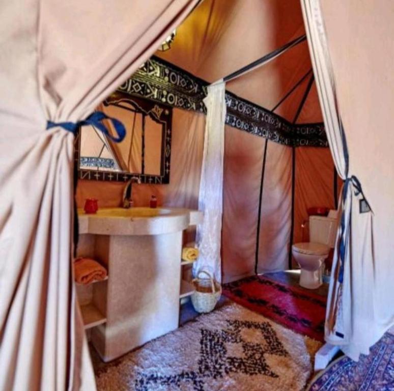 a bathroom with a sink and a toilet in a tent at Sandrela Luxury Camp in Merzouga