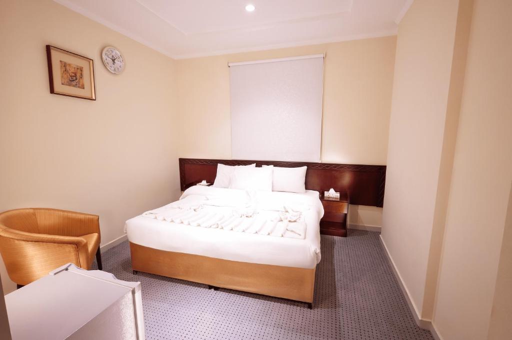 una habitación de hotel con una cama y una silla en فنـــــــدق الزائـــــــــــــــــريــن 1, en La Meca