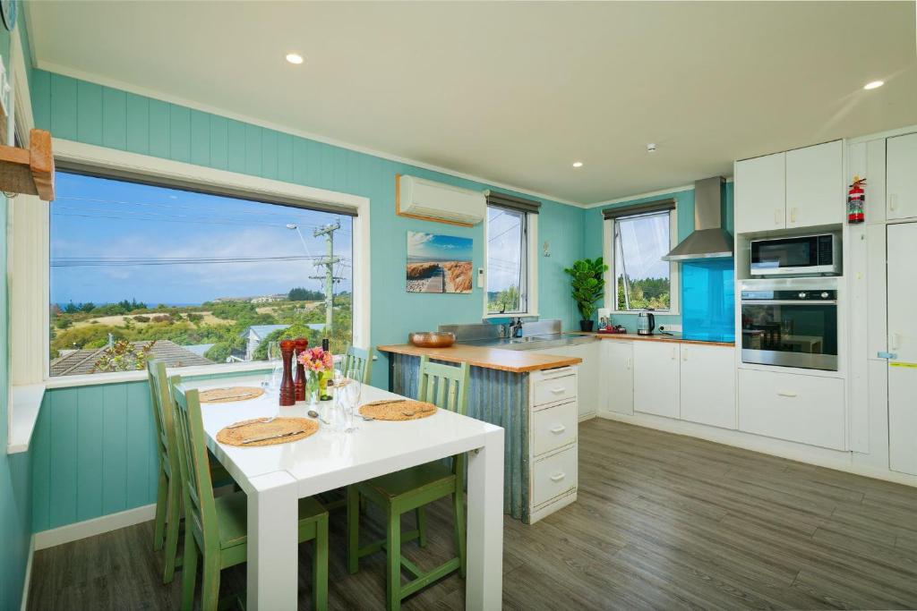 a kitchen with a white table and a large window at Classic Charm, Sea & Mountain Views, Family Fun - KK95170 in Kaikoura