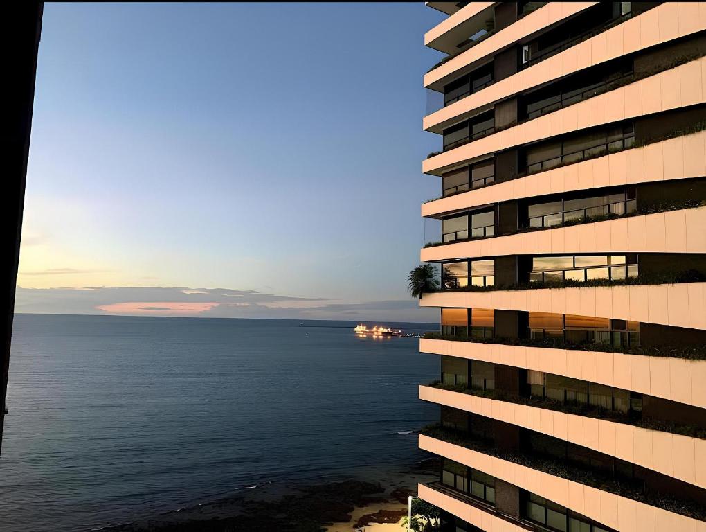 a tall building next to the ocean at sunset at Flat Particular em Blue Tree Towers Beira Mar Fortaleza in Fortaleza