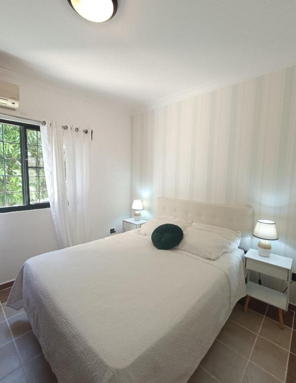 a white bedroom with a large bed and two lamps at Amplio, cómodo y junto a la playa de Boca Chica in Boca Chica