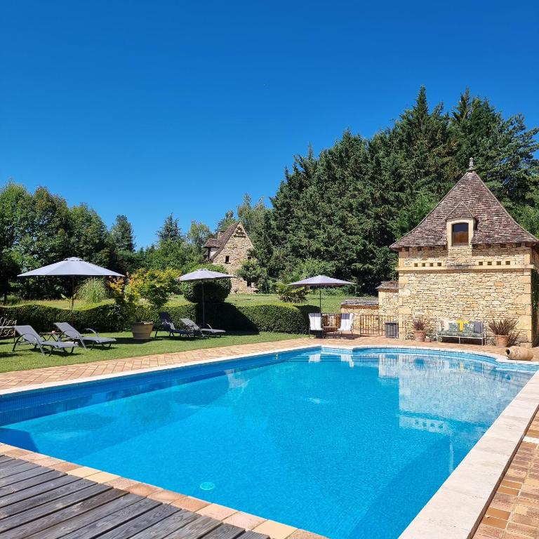 une piscine devant un bâtiment en pierre dans l'établissement Les Granges Hautes, maisons de vacances, proches de Sarlat avec piscine, parc,, à Saint-Crépin-et-Carlucet