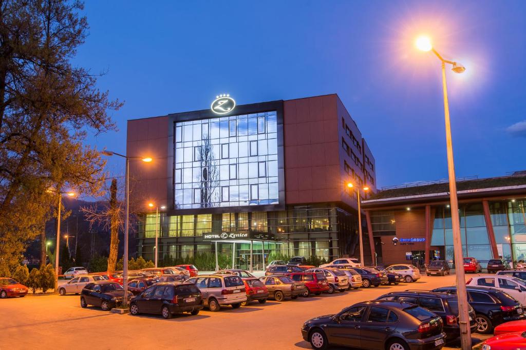 a parking lot with cars parked in front of a building at Hotel Zenica in Zenica