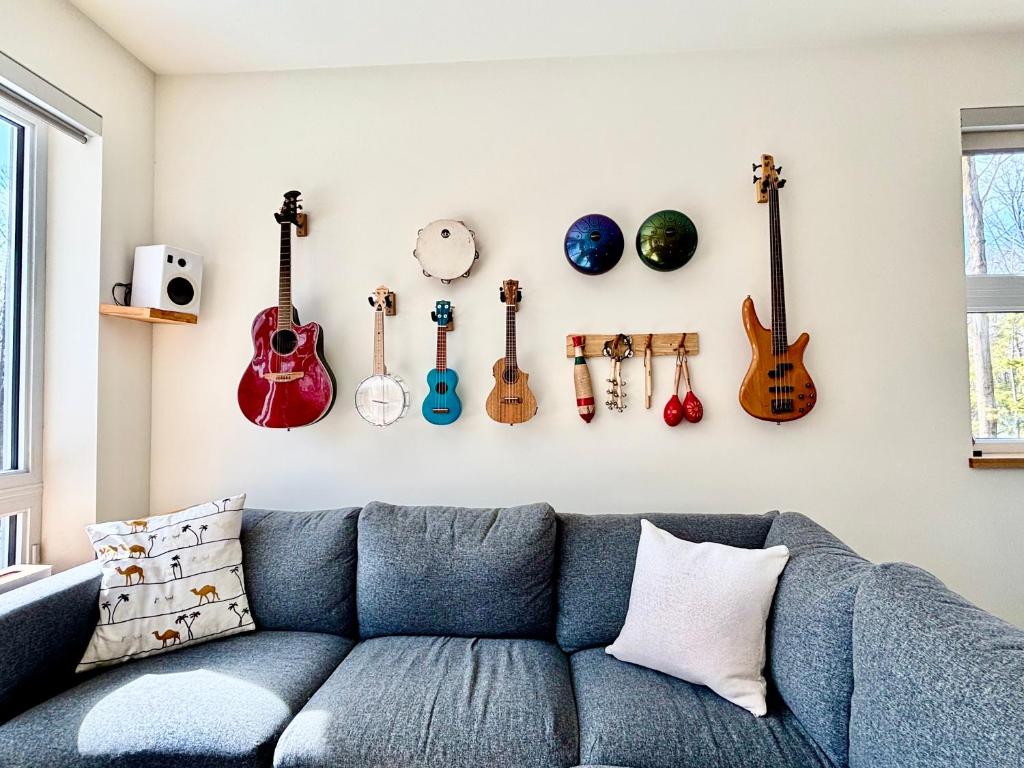 a living room with a blue couch and guitars on the wall at Le Camp Caché Shefford in Shefford
