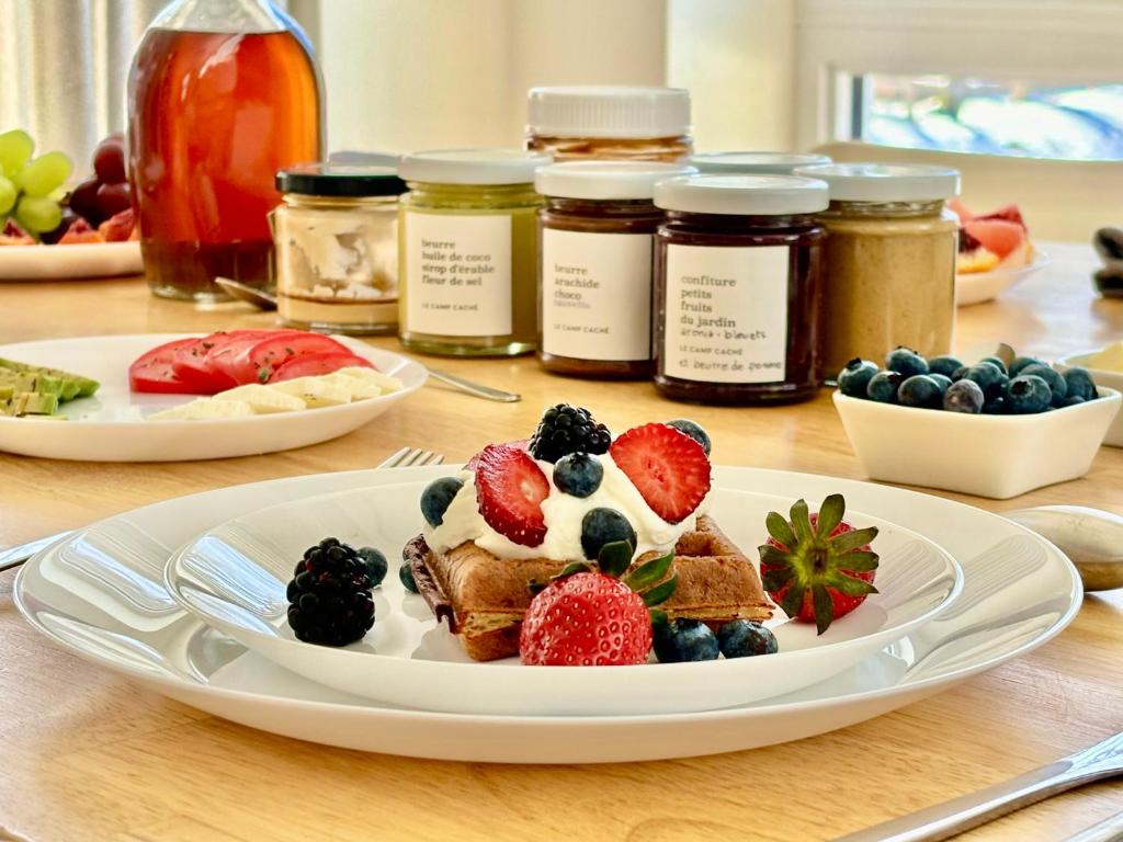 a table topped with a plate of food with fruit at Le Camp Caché Shefford in Shefford