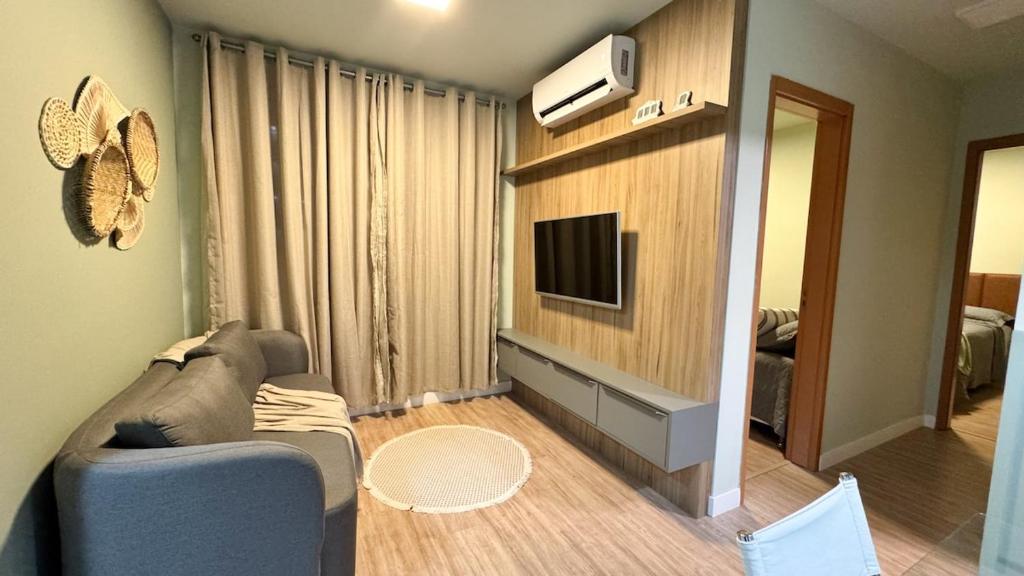 Una sala de estar con un sofá y un televisor de pantalla plana. en Apartamento Novo em Londrina, en Londrina