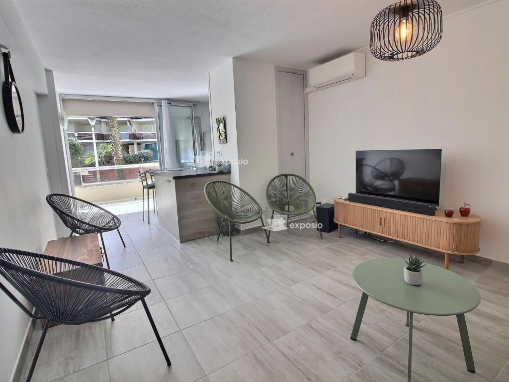 un salon avec une télévision à écran plat et des chaises dans l'établissement Appartement moderne climatisé en bord de mer à Canet, animaux admis, parking inclus - FR-1-732-93, à Canet