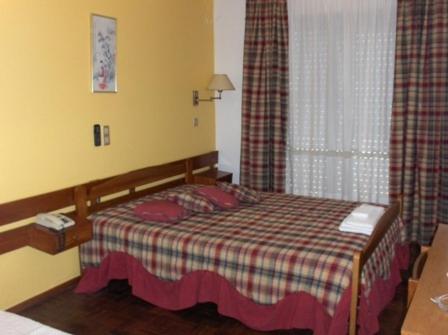 ein Schlafzimmer mit einem Bett mit einer karierten Decke und einem Fenster in der Unterkunft Sao Roque in Portimão