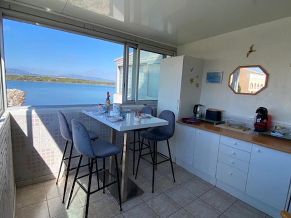 une cuisine avec une table et des chaises ainsi qu'une grande fenêtre dans l'établissement Port Leucate : Appartement T3 Lumineux pour 4 Pers, Climatisation, Parking - FR-1-798-57, à Leucate