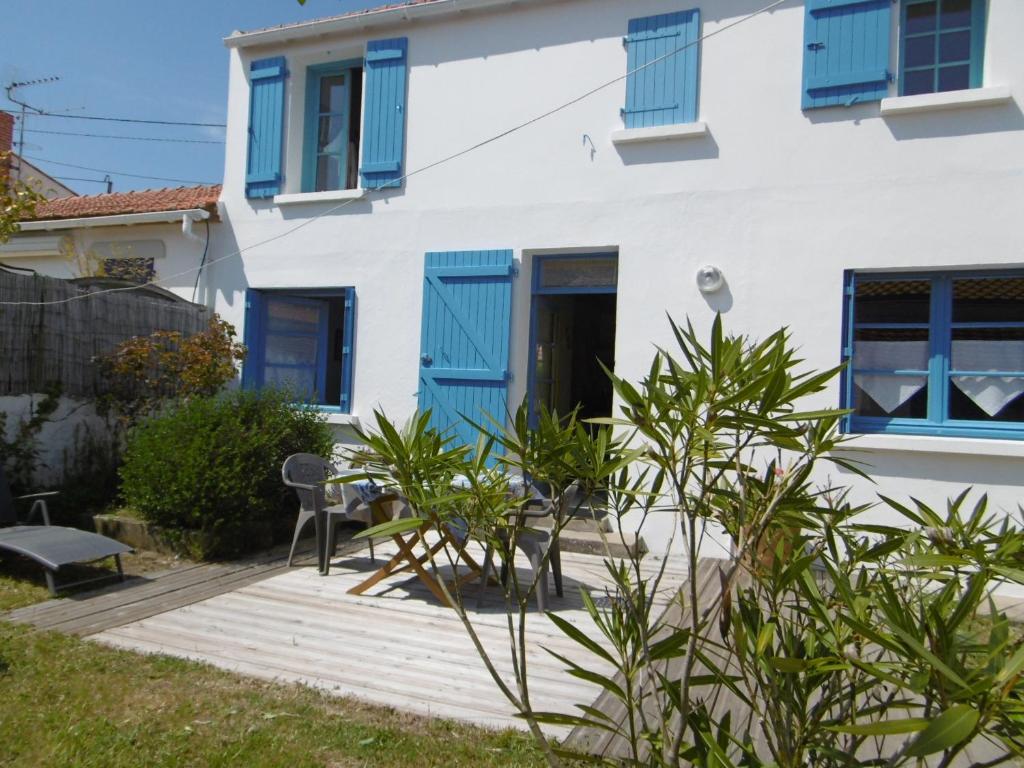une maison avec volets bleus et terrasse en bois dans l'établissement Maison près plage Noirmoutier pour 6 avec jardin - FR-1-823-141, à Barbâtre