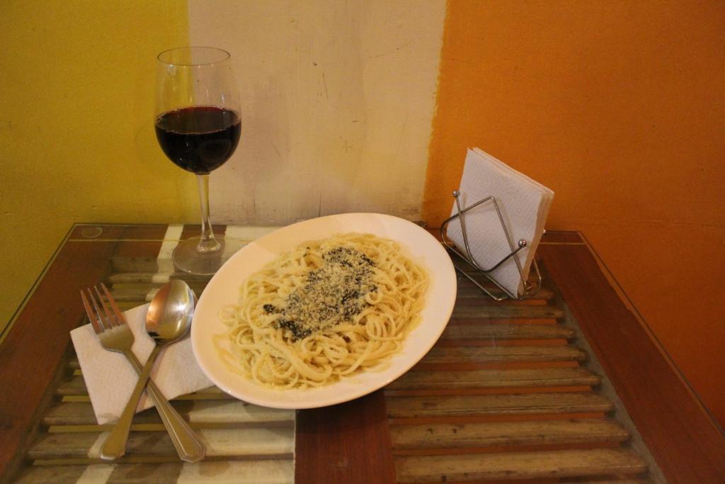 a plate of pasta and a glass of wine on a table at Aji Hostel in Santiago