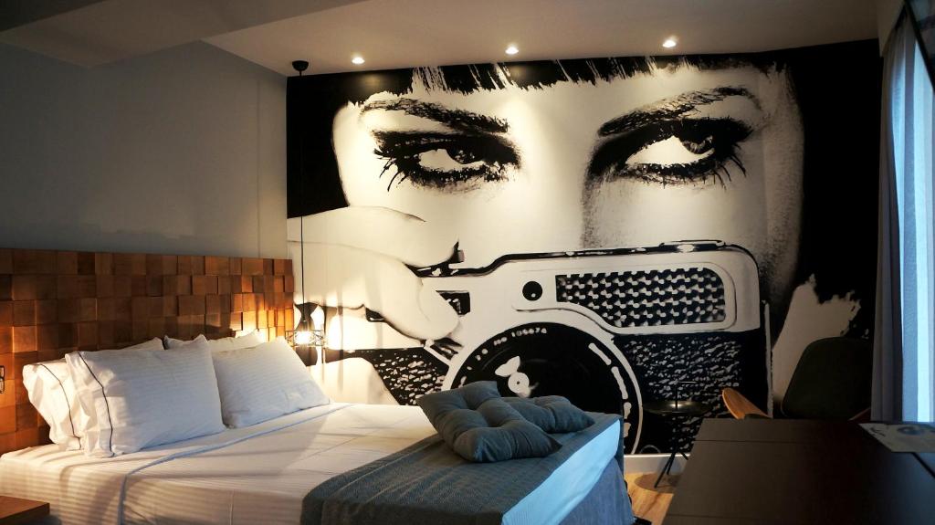 a bedroom with a bed with a painting of a face at Apollon Library Suites in Nafpaktos