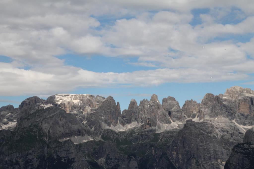 Une chaîne de montagnes avec des rochers et des nuages dans le ciel dans l'établissement Casa Frizzera, à Molveno