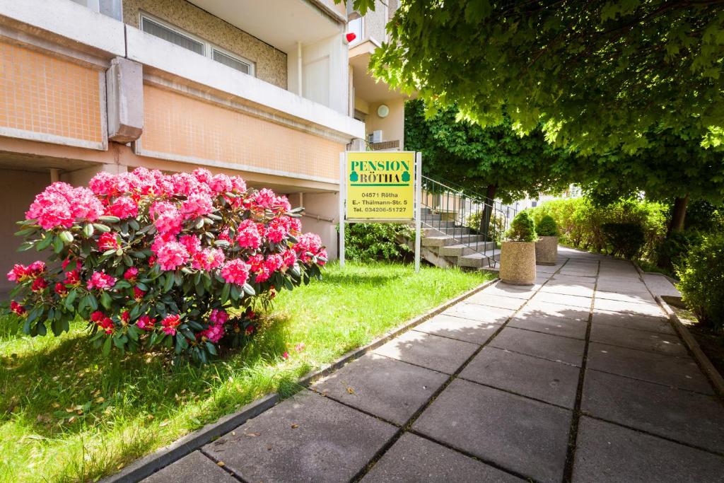 ein Schild vor einem Gebäude mit rosa Blumen in der Unterkunft Pension Rötha in Rötha