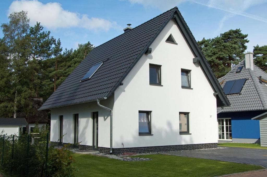 ein weißes Haus mit schwarzem Dach in der Unterkunft Dünenresidenz Glowe - Haus Emily in Glowe