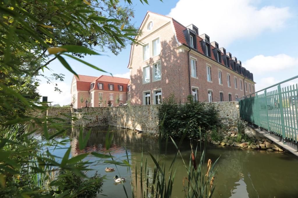 um grande edifício de tijolos ao lado de uma massa de água em Hofhotel Grothues-Potthoff em Senden