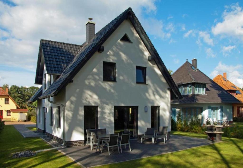 a white house with chairs and tables in the yard at Dünenresidenz Glowe - Haus Marie in Glowe