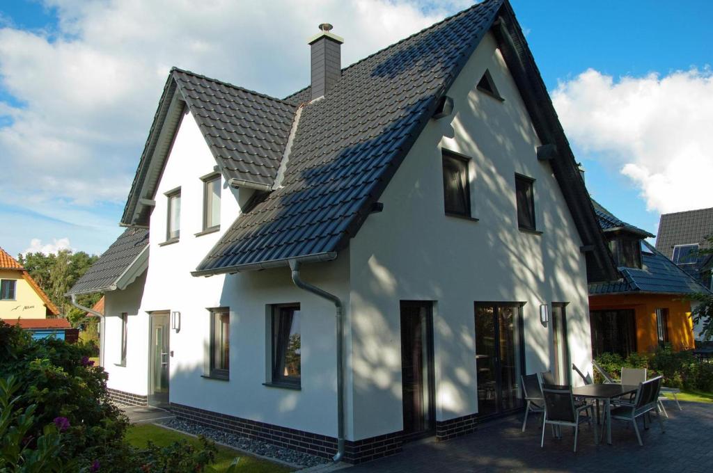 una casa bianca con tetto nero di Dünenresidenz Glowe - Ferienhaus Maxi 200 m zum Strand a Glowe
