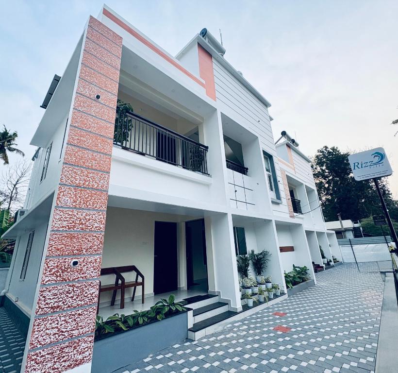 Un edificio blanco con un cartel delante. en Rizz Villa, en Trivandrum