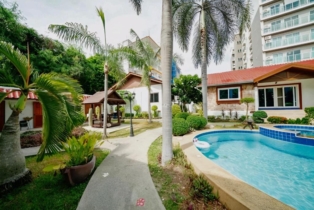 a house with a swimming pool and palm trees at Kotchaporn garden in Pattaya South