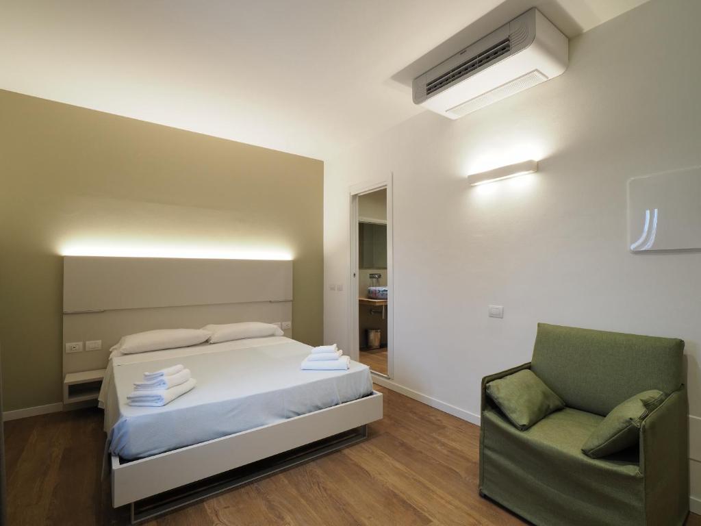 a bedroom with a bed and a green chair at Relais Dogana in Moniga