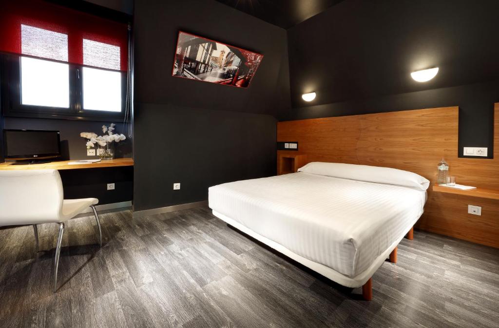 オビエドにあるExe Hotel El Magistralのベッドルーム(白いベッド1台、デスク、テレビ付)
