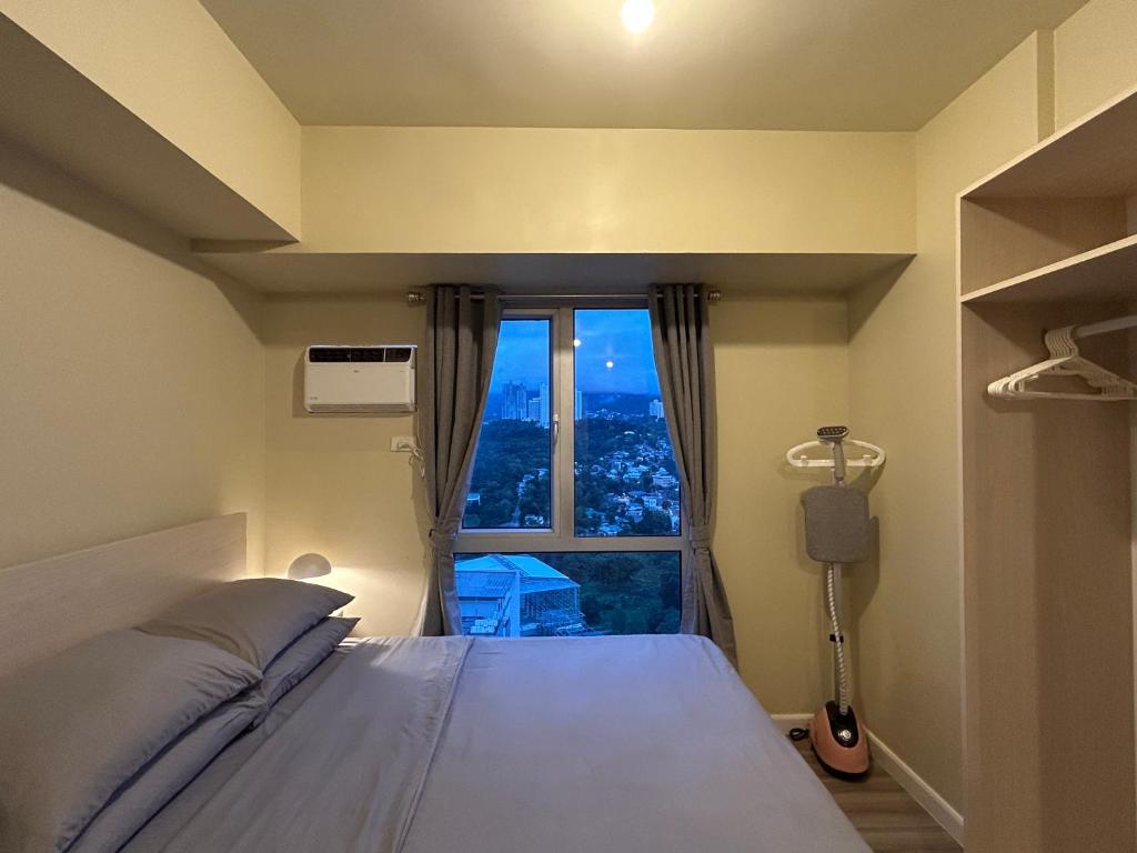 宿务Cushy Condo at Avida, IT Park Cebu的一间卧室，里面有一张床和一扇大窗户。