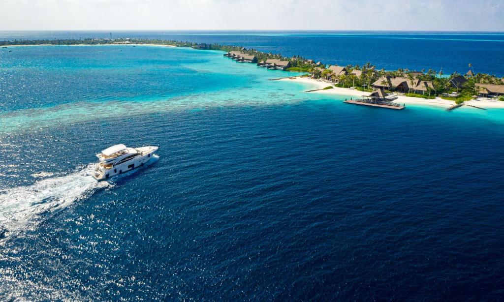an island with a boat in the water at Waldorf Astoria Maldives Ithaafushi in South Male Atoll