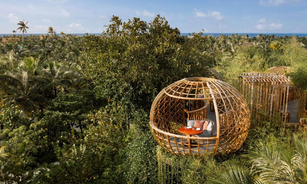 a bird cage with chairs in it in a field at Waldorf Astoria Maldives Ithaafushi in South Male Atoll