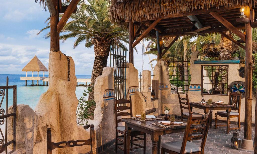 a restaurant on the beach with tables and chairs at Waldorf Astoria Maldives Ithaafushi in South Male Atoll
