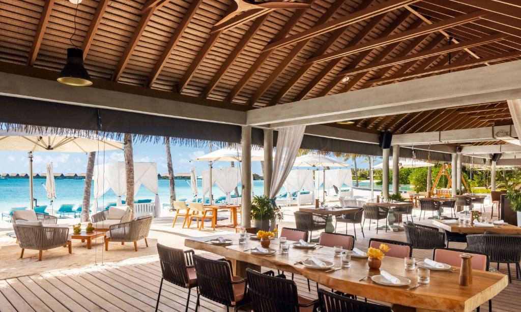 a restaurant with tables and chairs and the ocean at Waldorf Astoria Maldives Ithaafushi in South Male Atoll