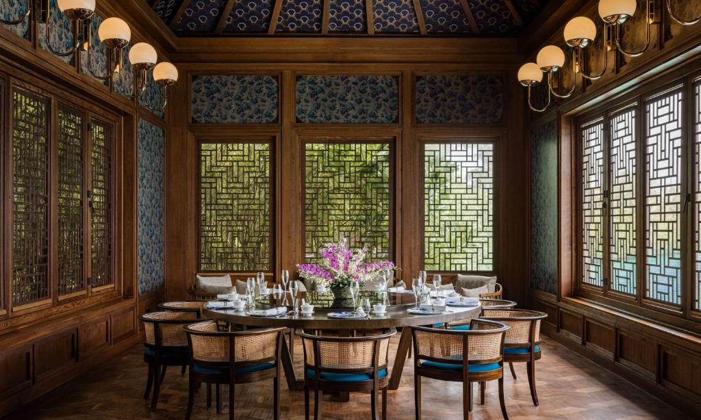 a dining room with a table and chairs and windows at Waldorf Astoria Maldives Ithaafushi in South Male Atoll