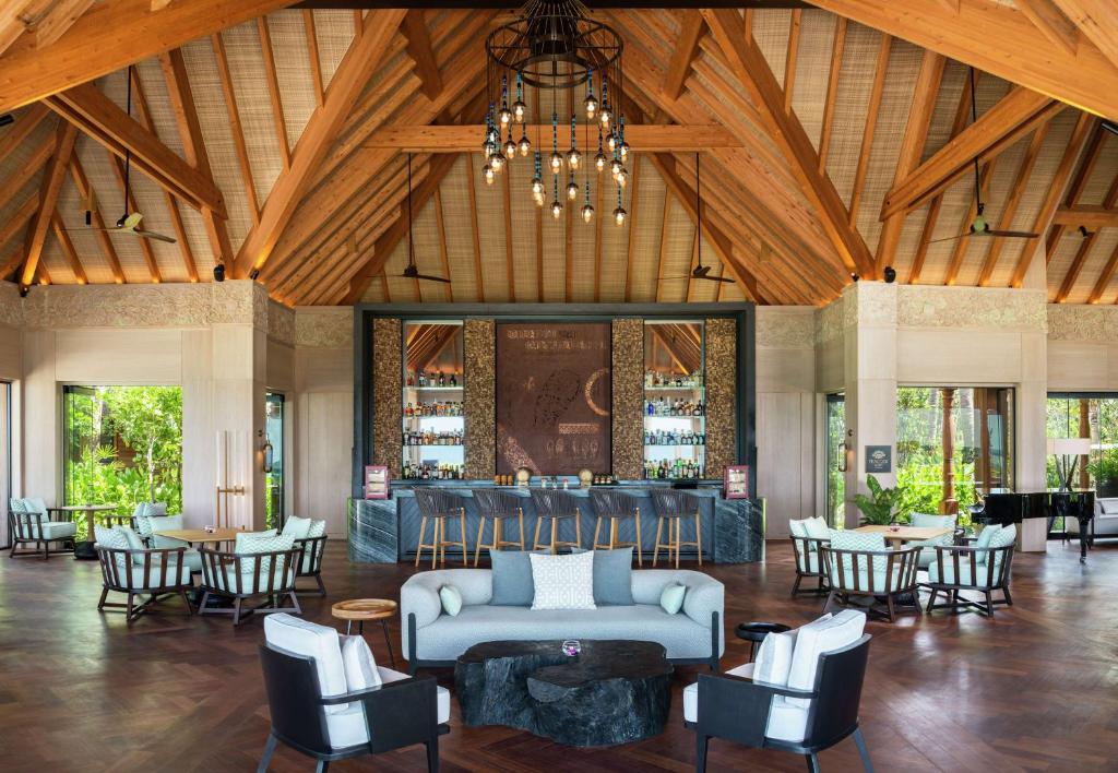 a lobby with a couch and tables and chairs at Waldorf Astoria Maldives Ithaafushi in South Male Atoll