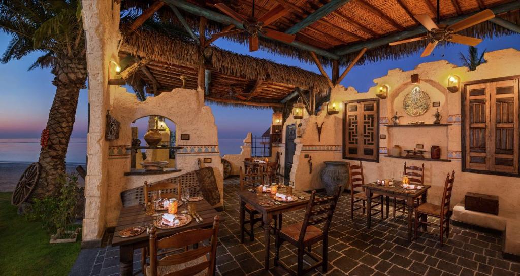a restaurant with tables and chairs and the ocean at Waldorf Astoria Maldives Ithaafushi in South Male Atoll