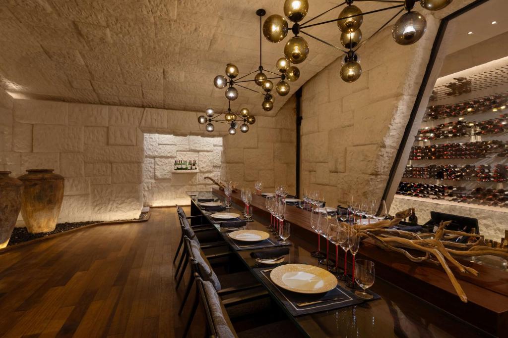 a dining room with a long table and a wine cellar at Waldorf Astoria Maldives Ithaafushi in South Male Atoll