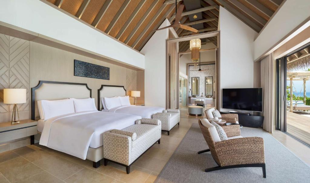 a bedroom with a large bed and a tv at Waldorf Astoria Maldives Ithaafushi in South Male Atoll