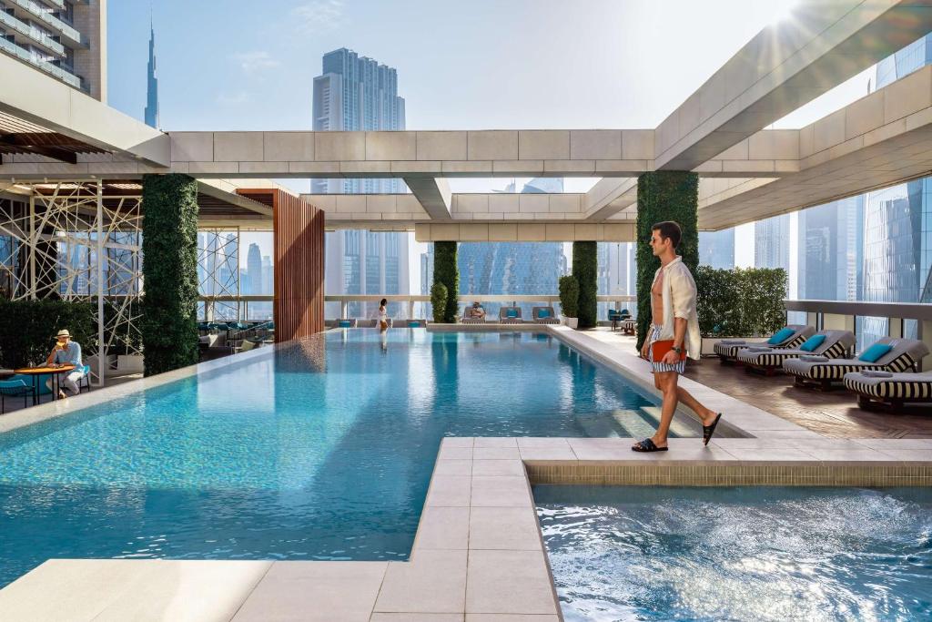 ドバイにあるWaldorf Astoria Dubai International Financial Centreの建物内のスイミングプールを歩く男