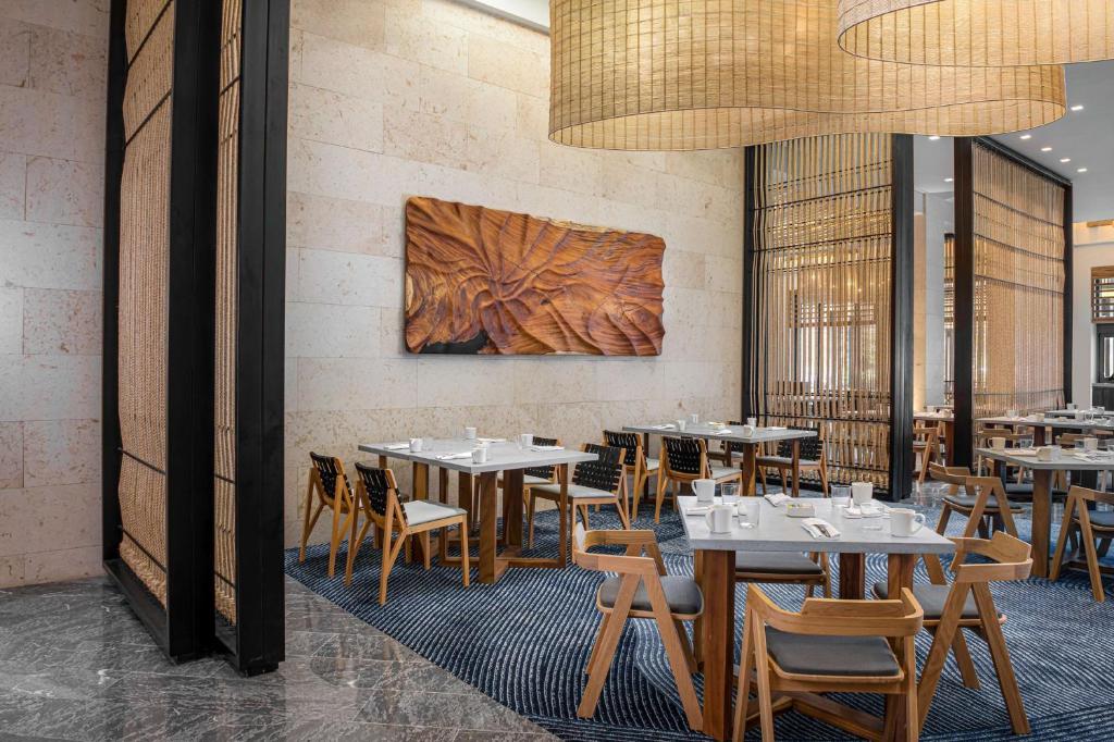 a restaurant with tables and chairs and a wall at Conrad Tulum Riviera Maya in Tulum