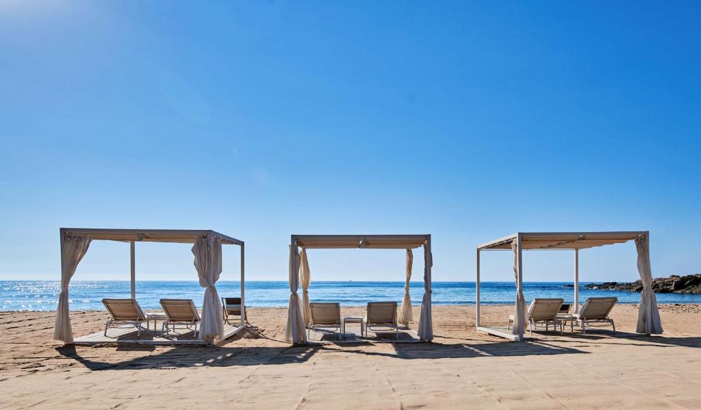 a group of chairs and a canopy on the beach at Conrad Chia Laguna Sardinia in Chia
