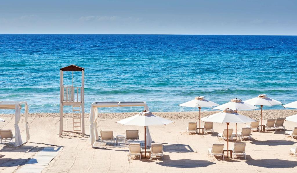 a group of chairs and umbrellas on a beach at Conrad Chia Laguna Sardinia in Chia
