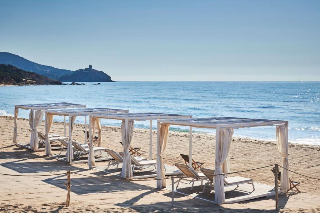 a row of tables and chairs on the beach at Conrad Chia Laguna Sardinia in Chia