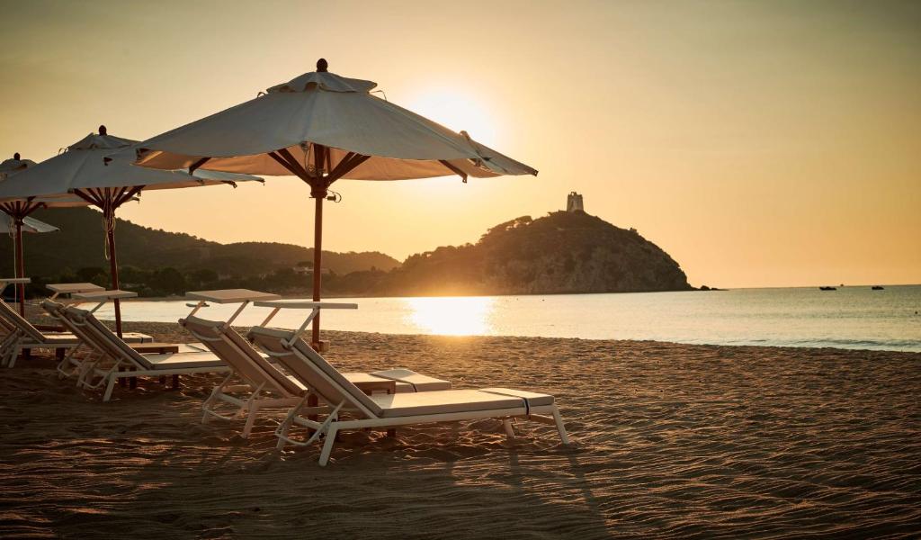a group of chairs and umbrellas on a beach at Conrad Chia Laguna Sardinia in Chia