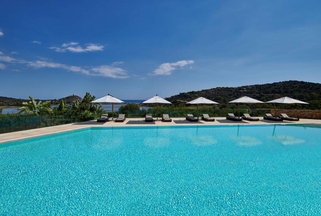 a swimming pool with chairs and umbrellas at Conrad Chia Laguna Sardinia in Chia