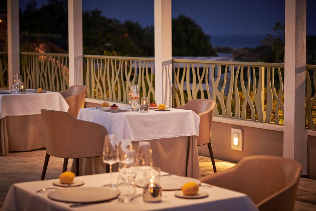 a restaurant with tables and chairs with a view of the ocean at Conrad Chia Laguna Sardinia in Chia