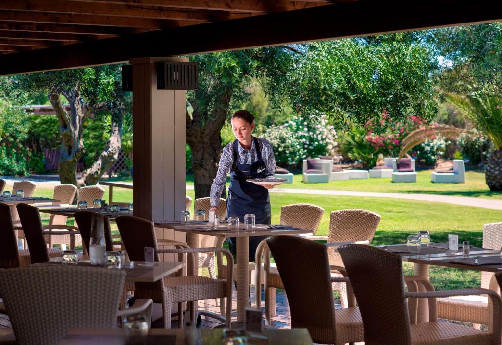 a man standing in front of tables in a restaurant at Conrad Chia Laguna Sardinia in Chia